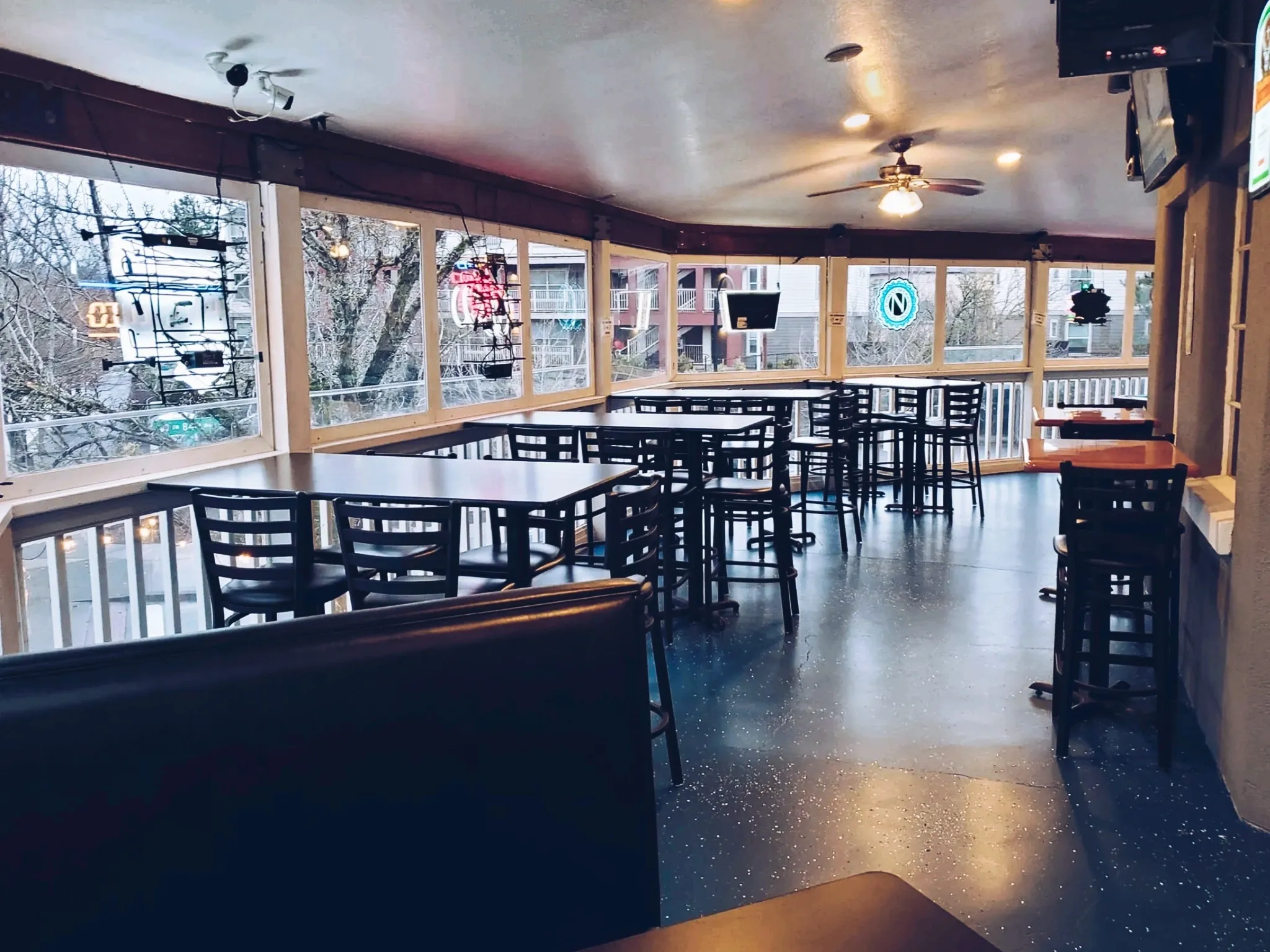 Covered upstairs patio with tables and large windows at Tualatin Station Bar and Grill